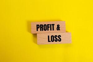 Profit and loss message written on wooden blocks with yellow background. Conceptual profit and loss symbol. Copy space. photo