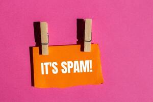 It's spam message written on ripped torn orange paper piece with pink background. Conceptual it's spam symbol. Copy space. photo