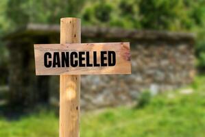 Cancelled message written on wooden sign with blurry nature background. Conceptual cancelled symbol. Copy space. photo