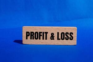 Profit and loss message written on wooden block with blue background. Conceptual profit and loss symbol. Copy space. photo