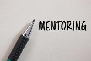 Mentoring message written on white paper with a pen. Conceptual mentoring symbol. Copy space. photo