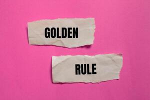 Golden rule message written on ripped paper pieces with pink background. Conceptual golden rule symbol. Copy space. photo