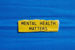 Mental health matters message written on ripped torn yellow paper piece with blue background. Conceptual mental health matters symbol. Copy space. photo