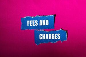 Fees and charges message written on ripped torn blue paper pieces with pink background. Conceptual fees and charges symbol. Copy space. photo