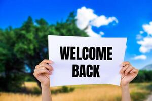 Welcome back message written on white paper with nature background. Conceptual welcome back symbol. Copy space. photo