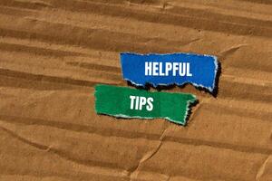 Helpful tips message written on ripped torn paper pieces with cardboard background. Conceptual helpful tips symbol. Copy space. photo