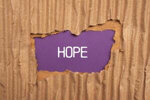 Hope message written on ripped torn cardboard paper with purple background. Conceptual hope symbol. Copy space. photo