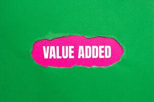 Value added message written on ripped torn green paper with pink background. Conceptual value added symbol. Copy space. photo
