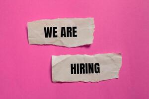 We are hiring message written on ripped paper pieces with pink background. Conceptual we are hiring symbol. Copy space. photo