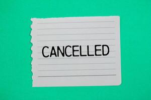 Cancelled message written on ripped torn paper piece with green background. Conceptual cancelled symbol. Copy space. photo