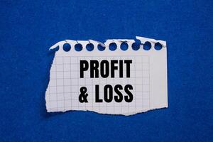 Profit and loss message written on ripped torn paper piece with blue background. Conceptual profit and loss symbol. Copy space. photo