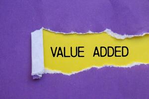 Value added message written on ripped torn purple paper with yellow background. Conceptual value added symbol. Copy space. photo