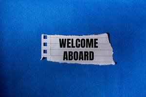 Welcome aboard message written on ripped torn paper piece with blue background. Conceptual welcome aboard symbol. Copy space. photo