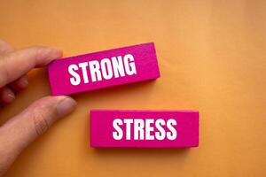 Strong stress message written on pink wooden blocks with orange background. Conceptual strong stress symbol. Copy space. photo