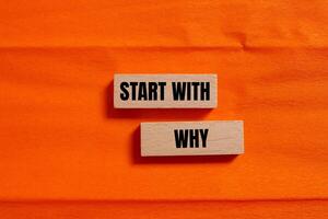 Start with why message written on wooden blocks with orange background. Conceptual start with why symbol. Copy space. photo