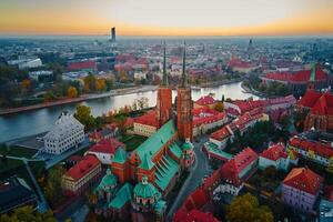 Aerial view of European city with Gothic churches and historic architecture in autumn season. St. John Cathedral on Ostrow Tumski at sunset. Cityscape panorama of Wroclaw, Poland photo