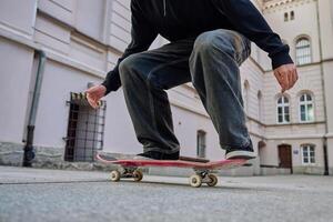 Skateboarder doing trick at urban street. Close up of skater wearing baggy jeans balancing on skateboard. Concept of youth subculture photo