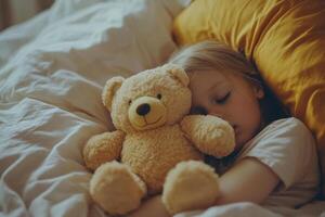 Child sleeps with plush stuffed toy bear in bed photo
