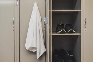 Open locker with towel and running shoes in gym changeroom photo