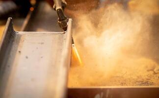 A man working with a torch cutting metal. Hazards of industrial work and safety measures in fabrication process. Metalworker cutting steel with a gas torch. Skilled labor and safety awareness. photo