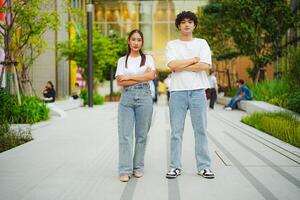 Confident young asian couple posing with arms crossed in urban setting photo