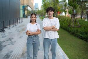 Confident young asian couple posing with arms crossed in urban setting photo