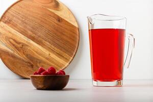 Red color drink in the glass jug on gray background. photo