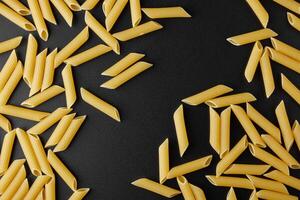 Raw pasta penne rigate with copy space on black background. photo
