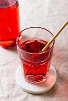 Red berries and fruits drink in the glass on the light background. photo