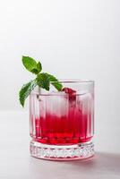 Raspberry cocktail with ice in a glass on a light background photo
