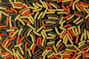 Raw pasta torti pattern on black background. photo