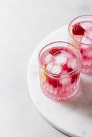 Raspberry cocktail with ice in a glass on a light background photo