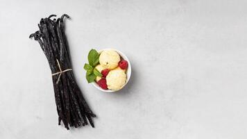 Vanilla beans and ice cream with raspberries on gray background photo