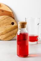 Red berries and fruits drink in the glass bottle on the light background. photo