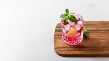 Raspberry cocktail with ice in a glass on a light background photo