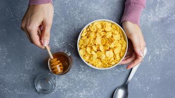 Corn flakes with honey in white bowl photo