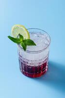 Cocktail with ice in a glass on a blue background photo