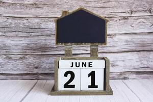 Chalkboard with June 21 date on white cube block on wooden table. photo