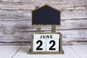 Chalkboard with June 22 date on white cube block on wooden table. photo