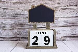 Chalkboard with June 29 date on white cube block on wooden table. photo