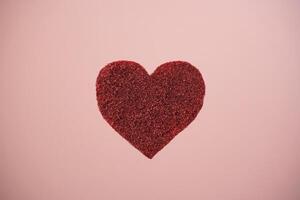 Red sparkle glitter heart on pink background. Minimalist holiday photo