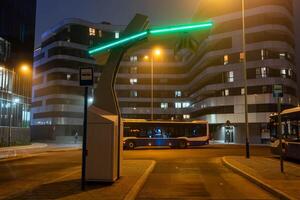 An electric bus stands at an empty bus stop and charges, a close up photo