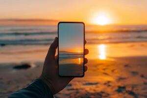 The smartphone displays an empty screen while being held at the beach, mirroring a beautiful sunset. Waves gently roll in as the sun sets, illuminating the scene photo