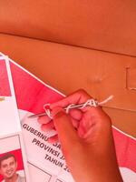 Cikancung, West Java, Indonesia - November 27, 2024. A hand holding a nail for voting. Ballot paper for the election of Governor and Regent. Regional general election. Democracy and voting rights. photo
