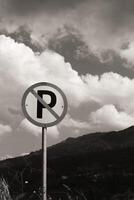 Monochrome Backgrounds No Parking sign post with cloudy sky and hill background. A silhouette of a round signpost on the side of the road. Copy Space. Graphic Resources. Road Traffic Signs. photo