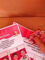 Cikancung, West Java, Indonesia - November 27, 2024. A hand holding a nail for voting. Ballot paper for the election of Governor and Regent. Regional general election. Democracy and voting rights. photo