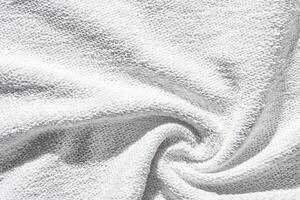 Soft white terry cloth fabric with textured surface and gentle folded swirl pattern for bath towels or robes. photo