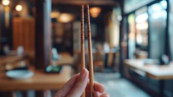 Authentic Asian Chopsticks Closeup Hand Holding Restaurant Blurred Background photo