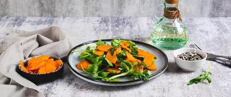 Roasted sweet potato and fresh arugula salad on a plate on the table web banner photo