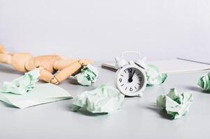 Burnt out man at work, crumpled papers, notebook and alarm clock on the desk photo